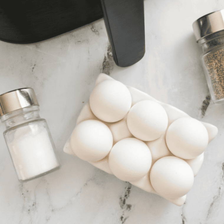 overhead closeup: 6 uncooked eggs in an egg holder with salt and pepper shakers to the side