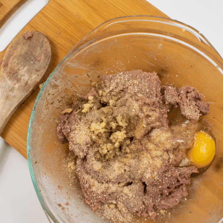 Mixing bowl with ground turkey sausage, egg, breadcrumbs, and minced garlic.