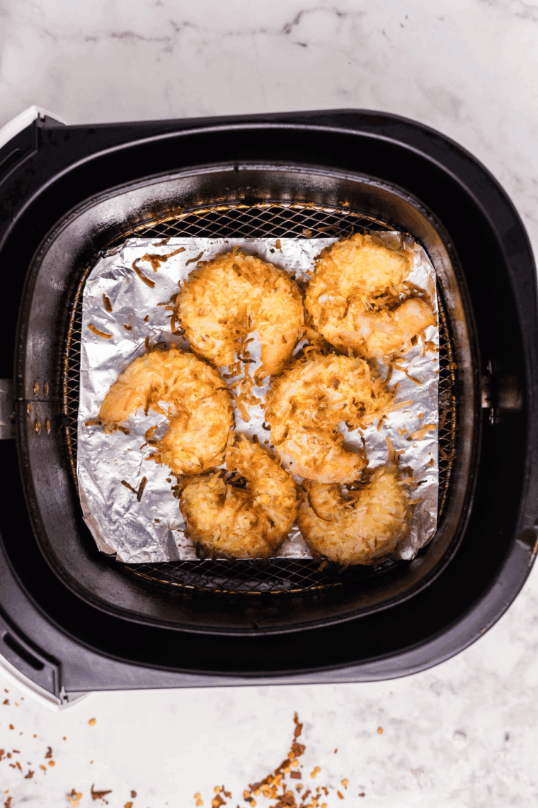 Plate of crispy, golden Captain D’s style coconut shrimp served with dipping sauce and lime wedges.