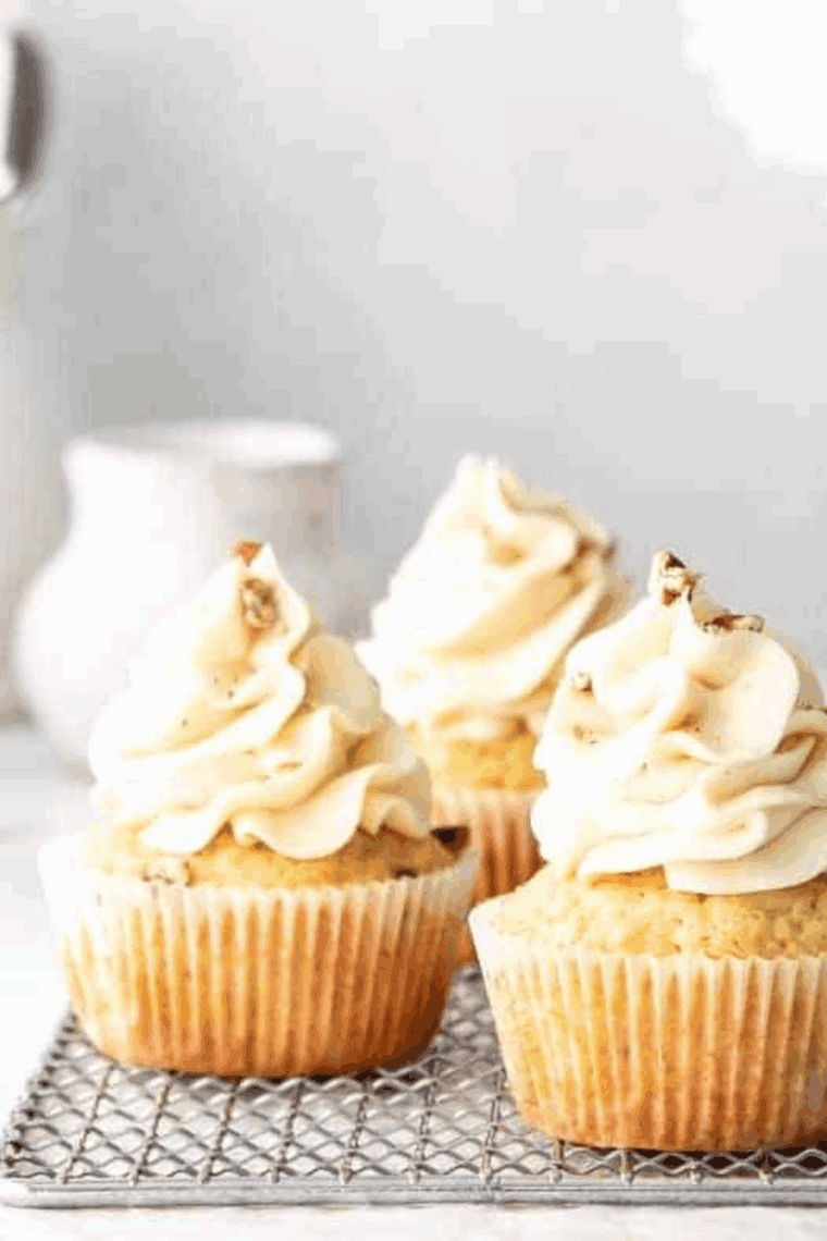 Moist and fluffy dairy-free cupcakes topped with creamy frosting on a white plate.
