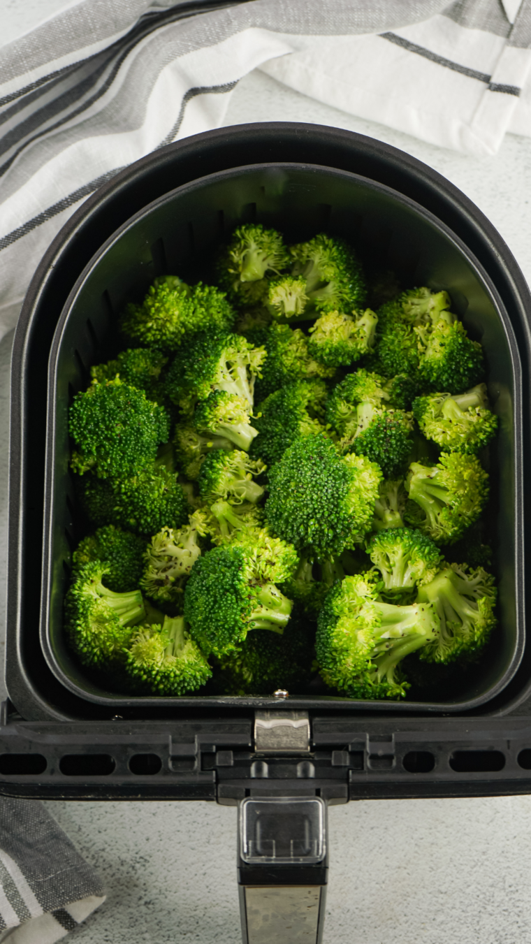 Placing broccoli in the air fryer basket.