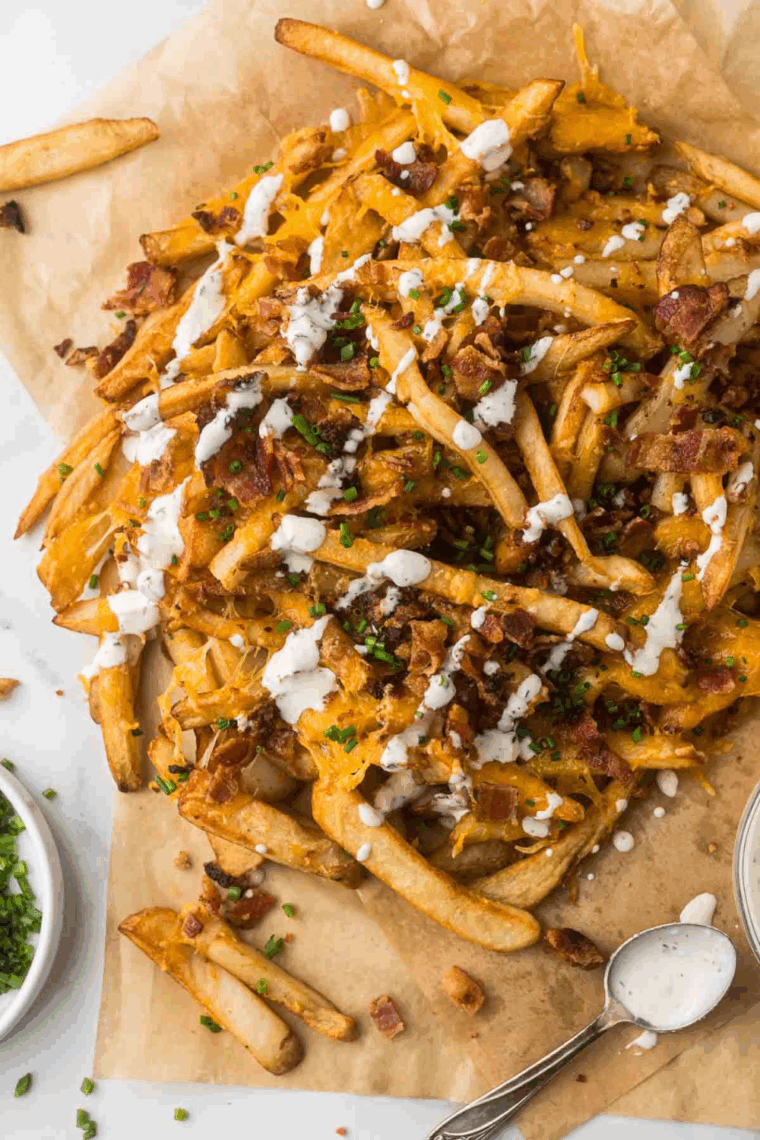 Plate of Texas Roadhouse-style cheese fries topped with bacon, melted cheddar, and sliced green onions.