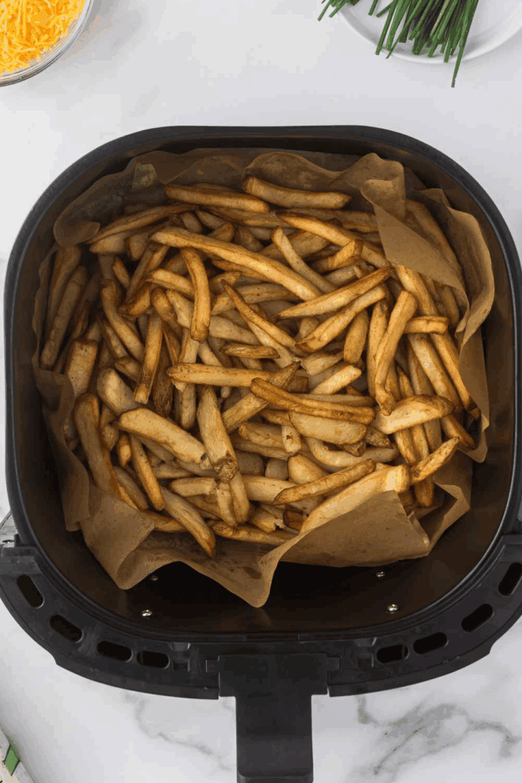 Cooked French fries in the air fryer basket.