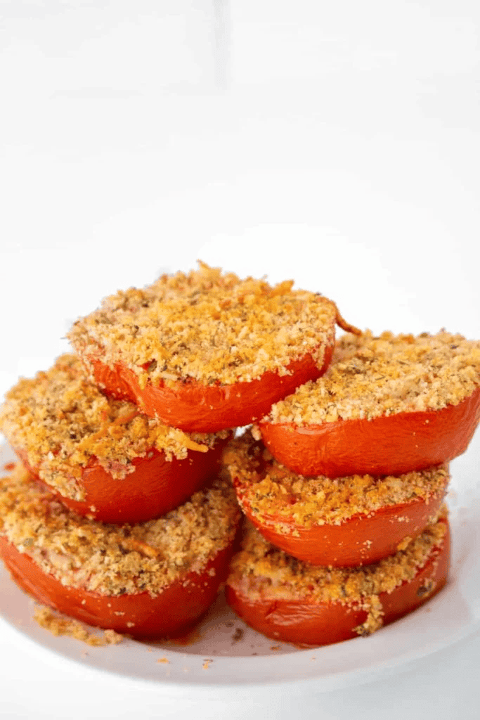side view: a stack of air fryer parmesan tomatoes on a white plate