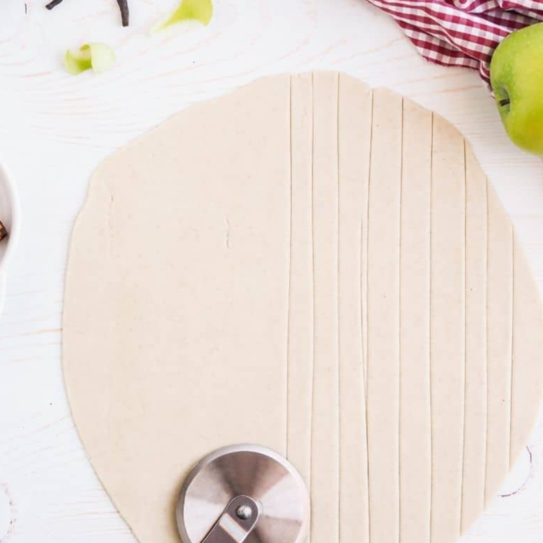 Rolling out cold dough on a floured surface and cutting it into 1/3 inch wide strips with a pizza cutter.