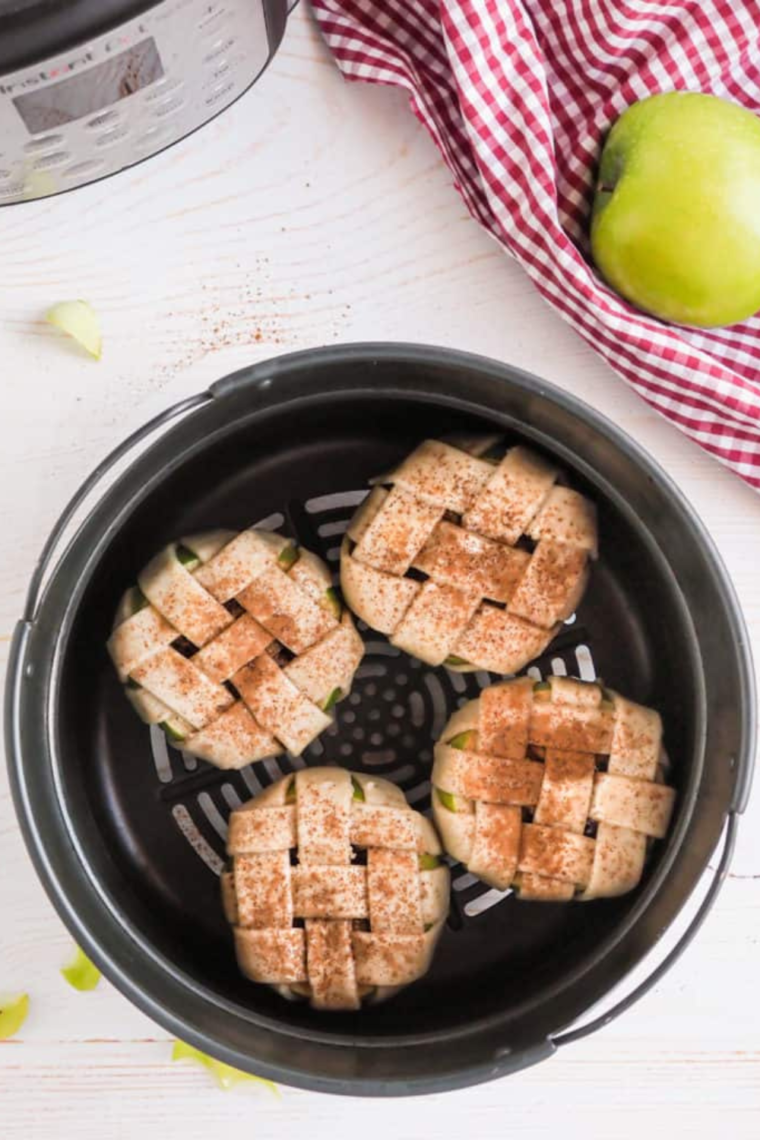 Placing apples into the air fryer basket and cooking until the crust is golden brown and the filling is bubbling, then serving with caramel drizzle and vanilla ice cream.