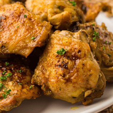 Alt Tag: Golden-brown air fryer chicken thighs cooked in a Ninja Crispi, served on a plate with fresh herbs.
