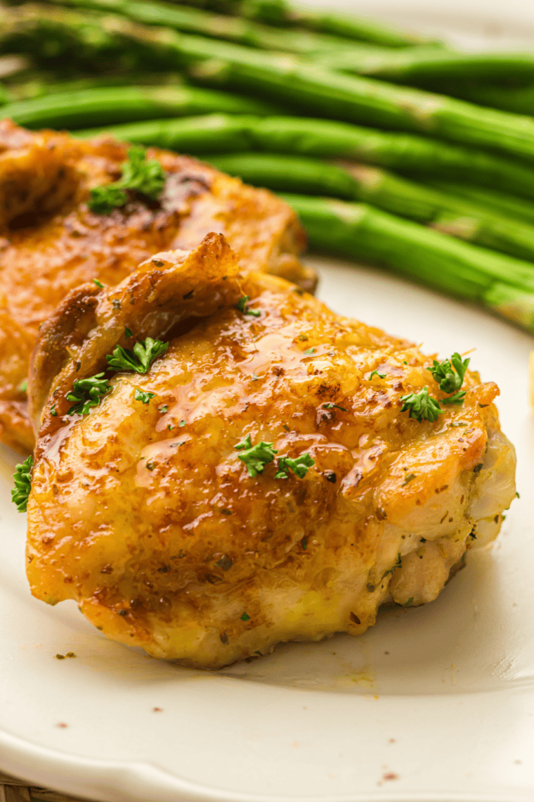 Golden-brown crispy chicken thighs fresh from a Ninja Crispi air fryer, served on a plate with herbs.