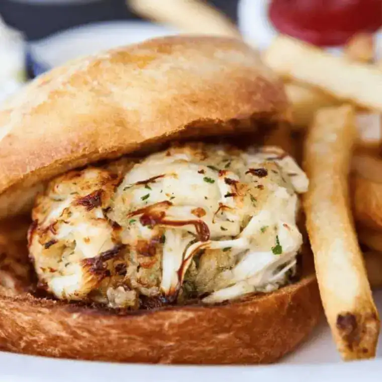 Air fryer crab cake sandwich assembled on brioche bun with lettuce, tomato, remoulade sauce, and a crispy crab cake inside.
