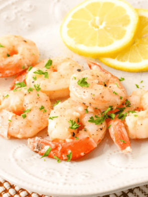 "Air fryer garlic butter shrimp garnished with parsley and lemon wedges"