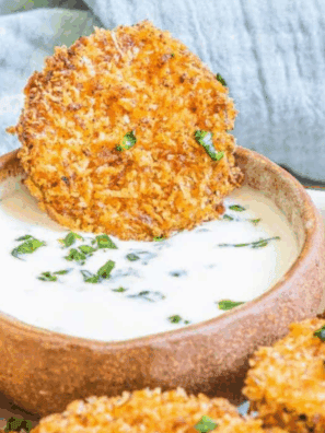 Golden air-fried zucchini crisps coated in parmesan cheese, served on a plate for a crunchy snack or appetizer.