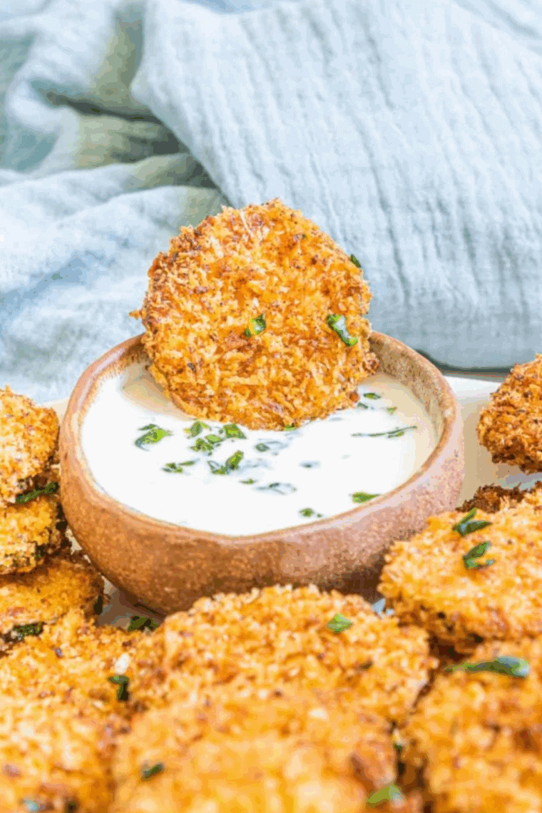 Golden, crispy zucchini rounds coated in parmesan cheese, fresh from the air fryer and served on a plate.