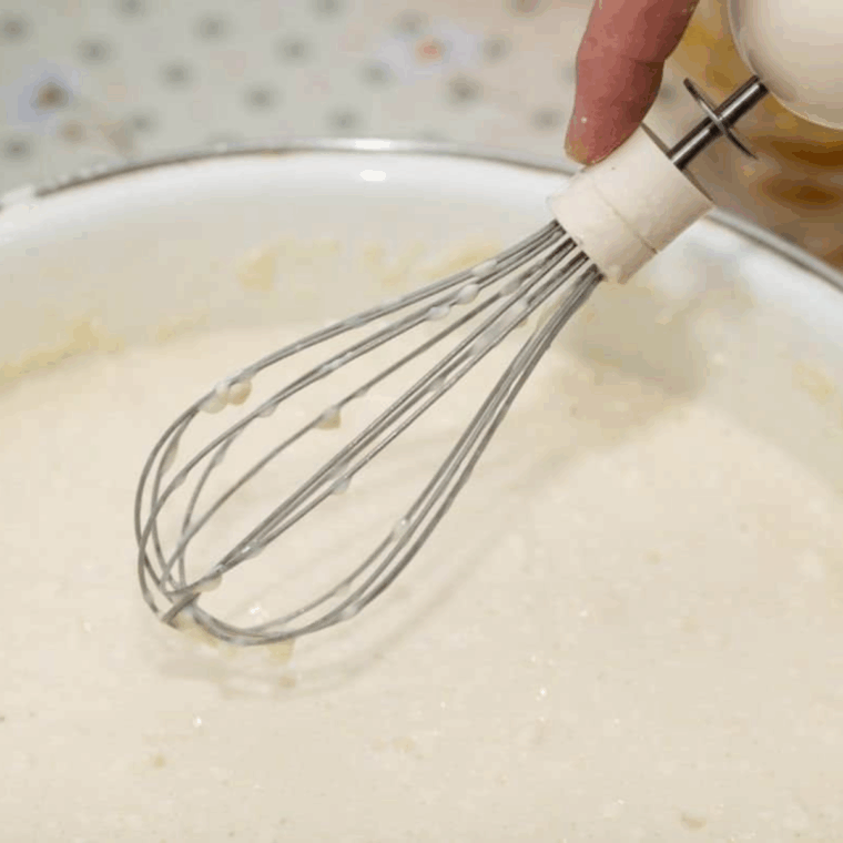 Whisking dry ingredients, then folding them into mashed bananas and wet ingredients to form banana cake batter.