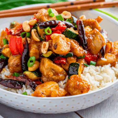Air fryer crispy Kung Pao chicken with peanuts and vegetables on a plate.