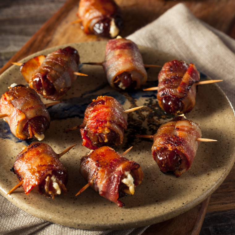 Plate of crispy Air Fryer Bacon-Wrapped Dates stuffed with creamy cheese, served as a delicious appetizer.