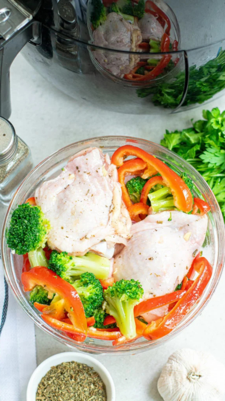 Seasoning Chicken Thighs: Close-up of seasoned chicken thighs being coated with olive oil, garlic, and herbs in a mixing bowl.