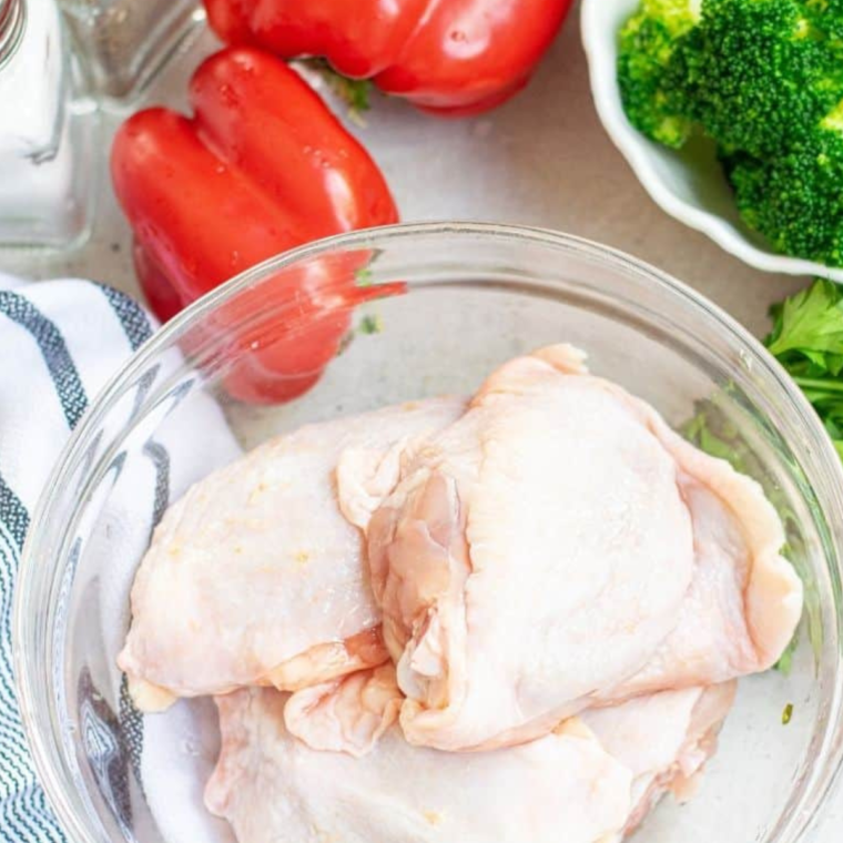 Preparing Ingredients: A table filled with ingredients for Air Fryer Chicken Thighs and Vegetables, including chicken thighs, bell peppers, broccoli, and seasonings.