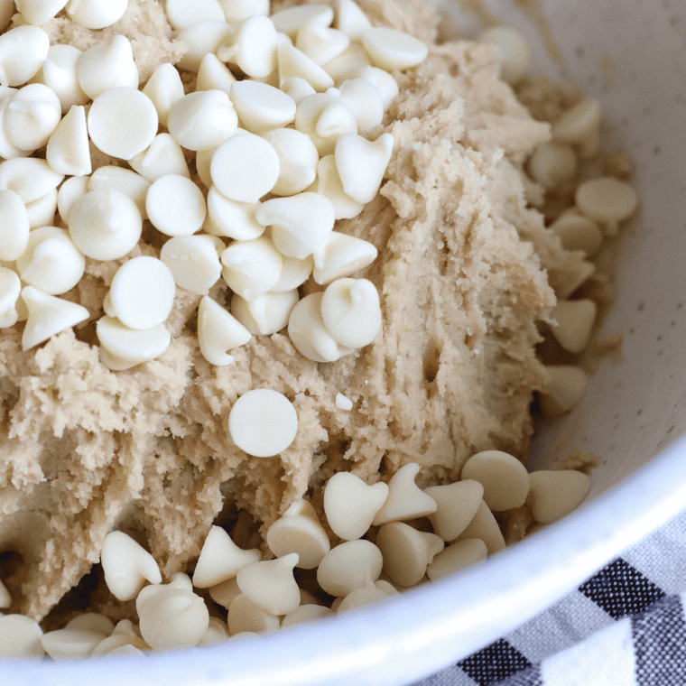 Folding white chocolate chips evenly into cookie dough.