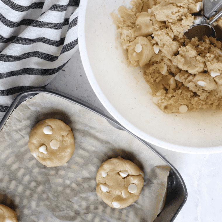 Scooping cookie dough balls onto a parchment-lined air fryer tray.
