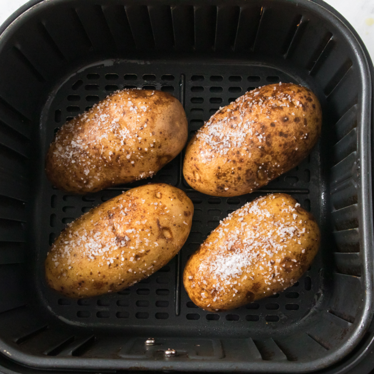 Potatoes coated with olive oil and sea salt sitting in air fryer basket