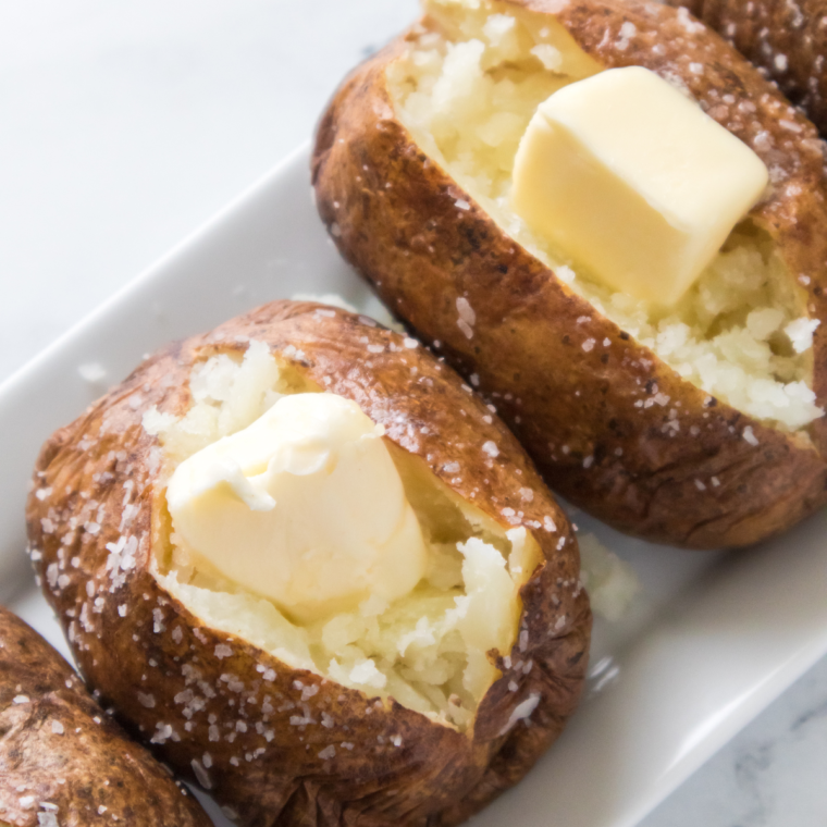 baked potato and pats of butter on a tray