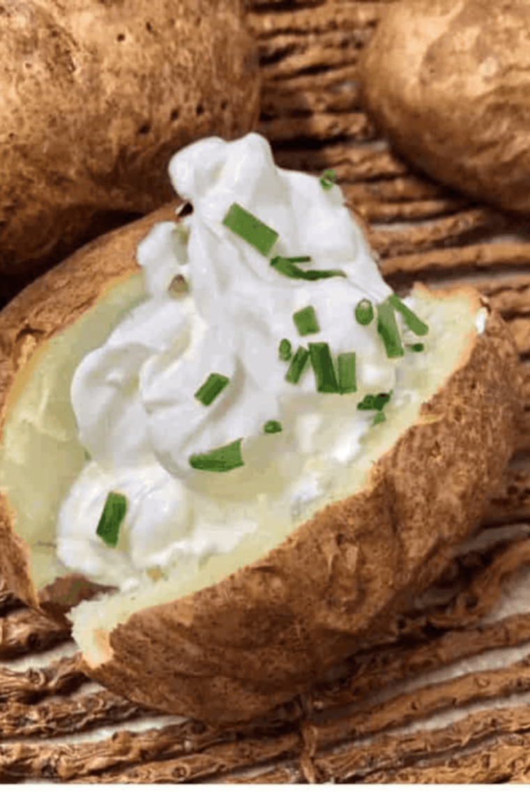 baked potato sour cream and chives picture, with out cooked potatoes in the background