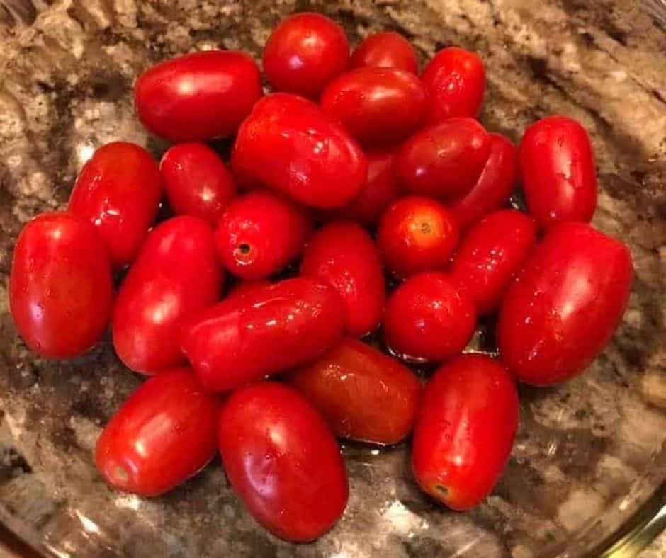 Air Fryer Roasted Cherry Tomatoes cherry tomaotes in bowl with olive oil, and spices.