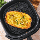 Air fryer spaghetti squash strands fluffed with a fork on a dark red platter