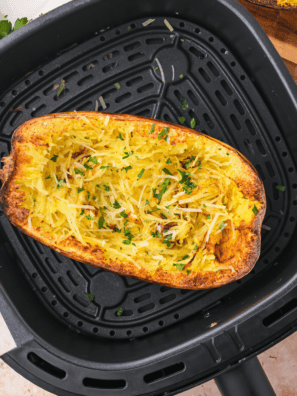 Air fryer spaghetti squash strands fluffed with a fork on a dark red platter