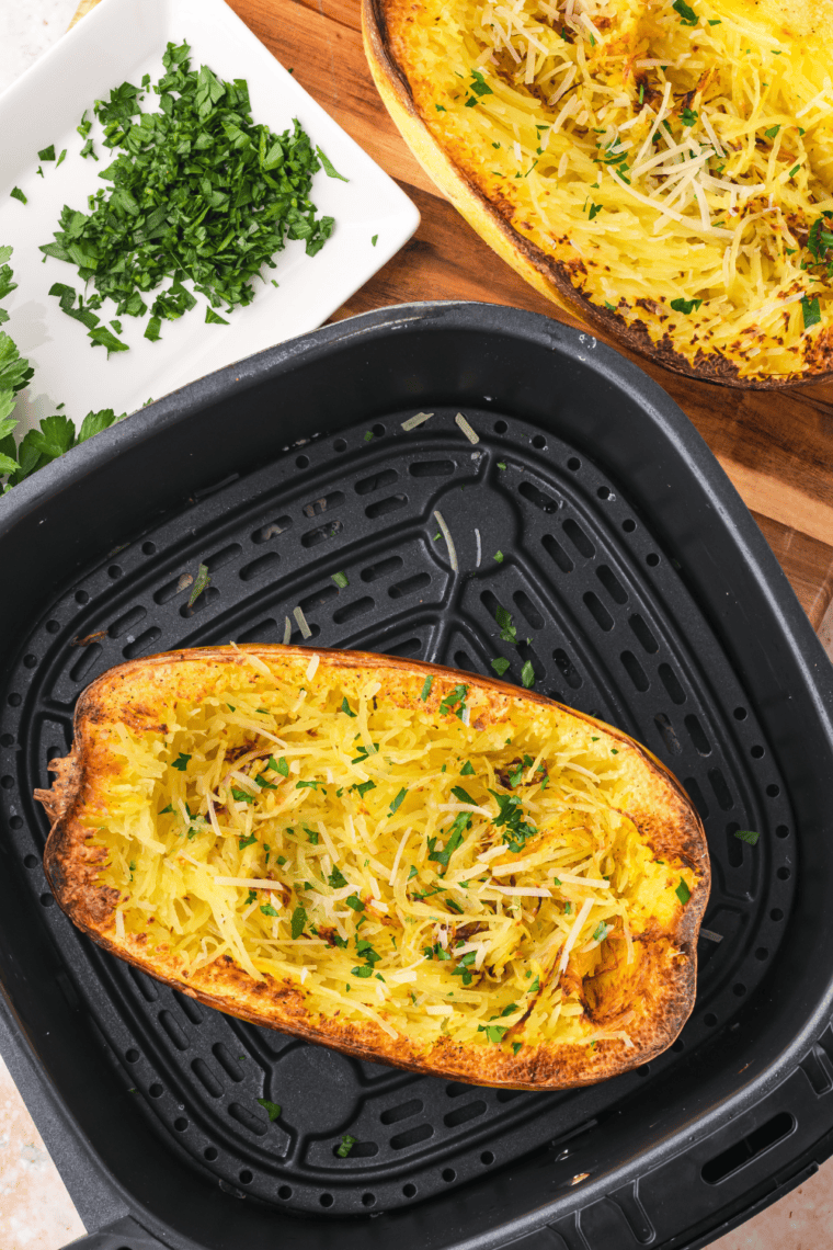 Two forks scraping cooked spaghetti squash into strands inside the shell