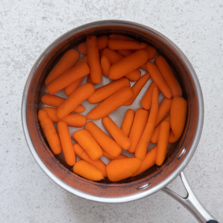 Baby carrots stirred with brown sugar, butter, salt, and water in a skillet for copycat Bob Evans glazed carrots.
