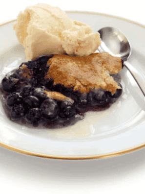 Easy air fryer blueberry cobbler with golden topping and bubbling blueberries in a baking dish.