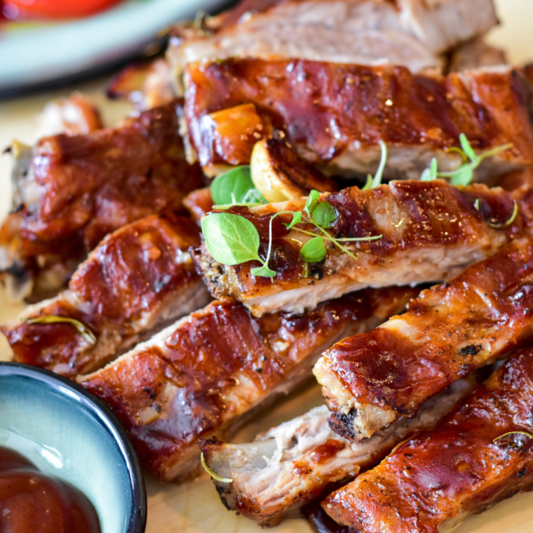 Instant Pot BBQ Baby Back Ribs on a serving platter with barbecue sauce.