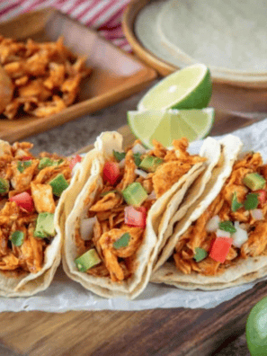 Shredded Instant Pot salsa chicken in a white bowl topped with fresh cilantro and a lime wedge