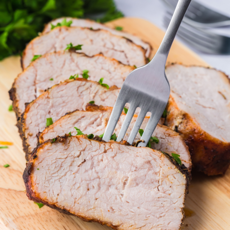 Sliced marinated pork tenderloin cooked in air fryer on a serving plate with caramelized edges