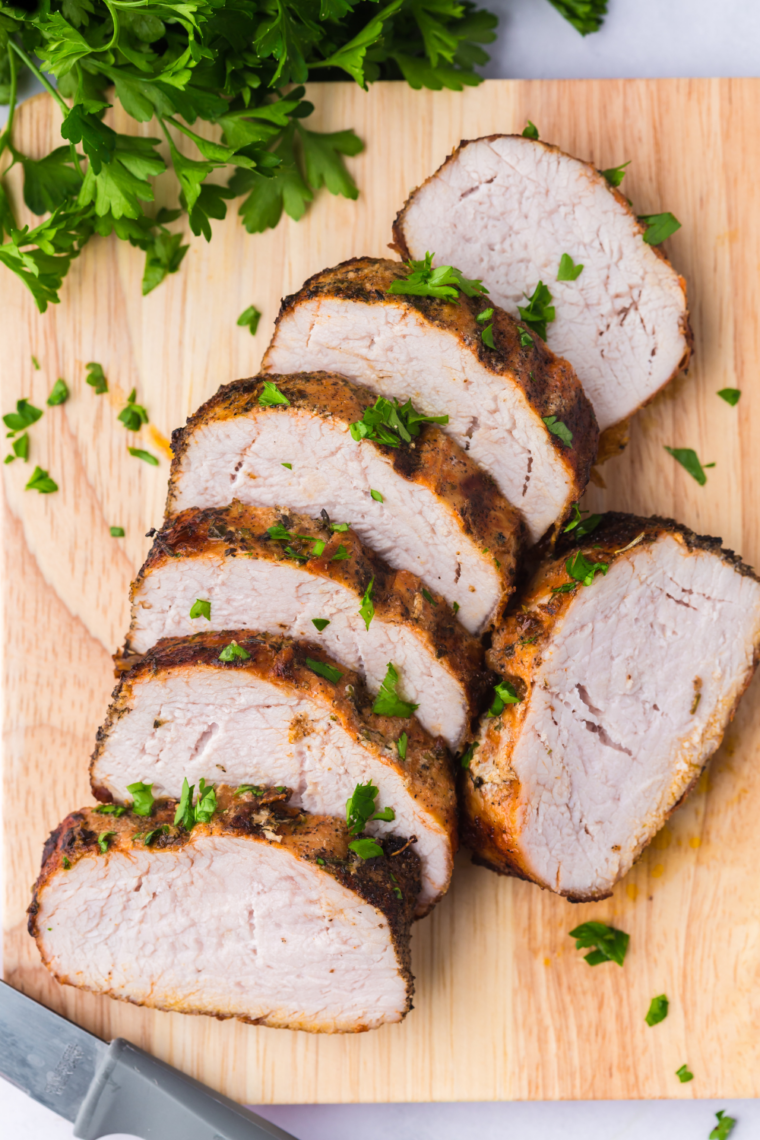 Sliced marinated pork tenderloin cooked in air fryer on a plate with caramelized edges