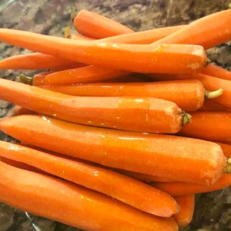 Seasoned whole carrots in an air fryer basket