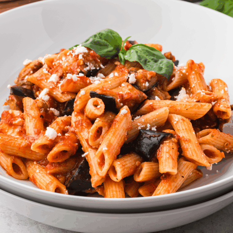 Simmering the red tomato sauce gently in a pot on the stovetop to develop the deep, balanced flavor.
