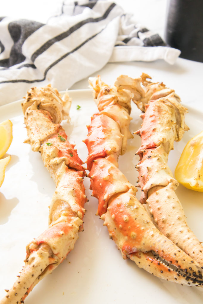 Air fryer crab legs served on a white plate, placed on a kitchen counter.