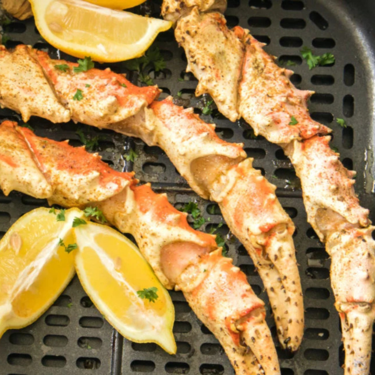 Deliciously cooked Air Fryer Crab Legs served on a white plate with butter and seasoning.