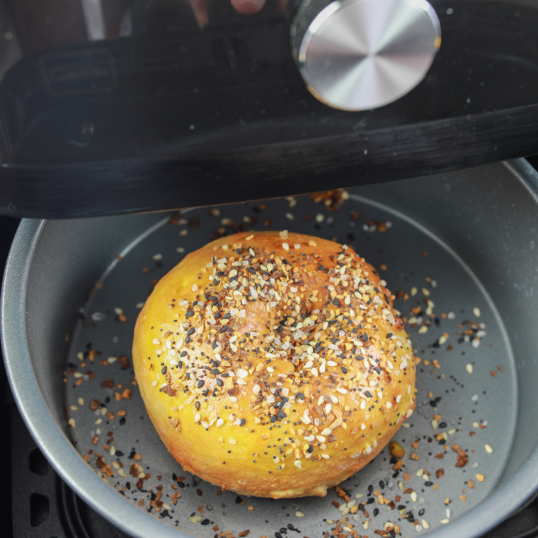 Four homemade everything bagels arranged in a single layer inside an air fryer basket