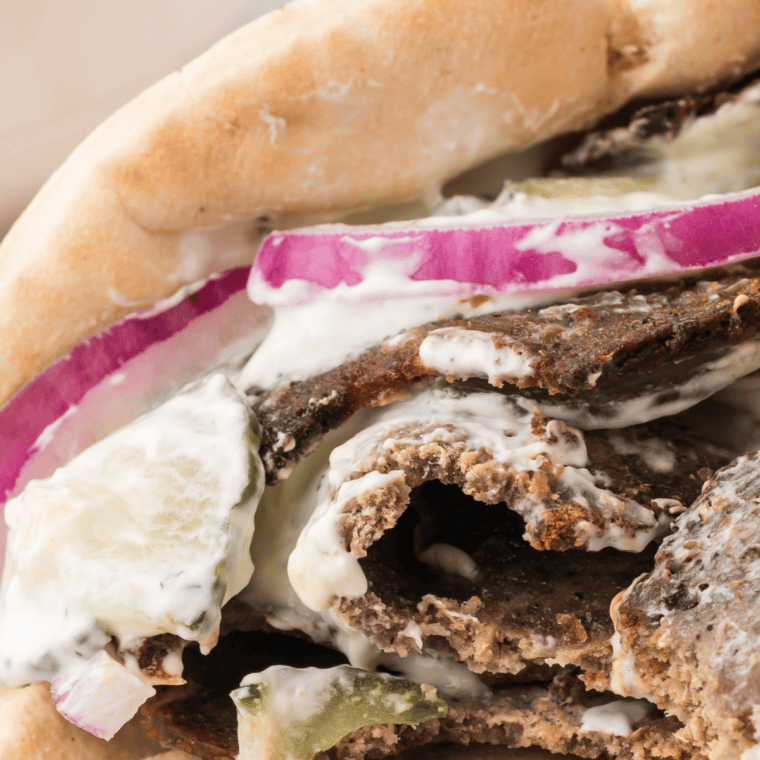 Sliced air fryer lamb gyro meat served in warm pita with tzatziki, tomatoes, and onions.