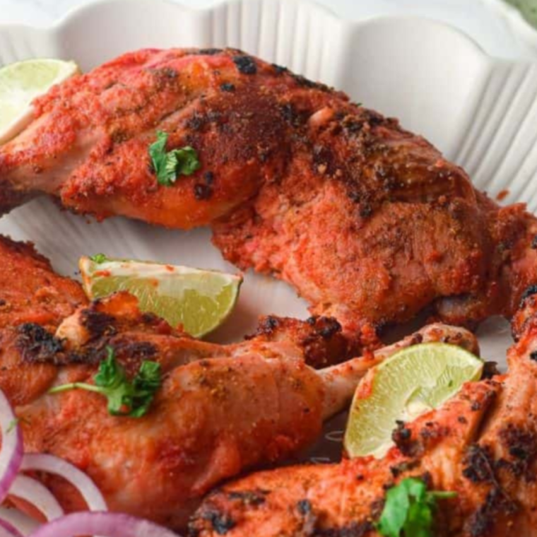 Close-up of air fryer chicken tandoori on a plate, showcasing golden-brown, spice-coated pieces of chicken with vibrant tandoori seasoning.