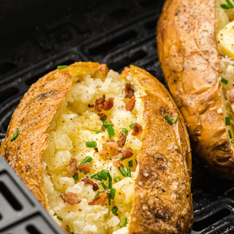 Crispy Copycat Outback Baked Potatoes with salt-crusted skins and fluffy insides served on a white plate with butter and chives.