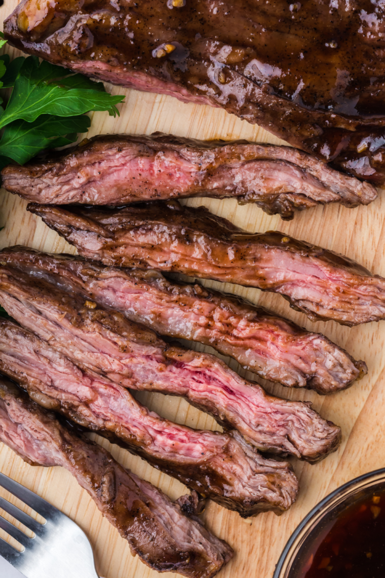 Sliced air fryer skirt steak on a plate with browned edges and fresh herbs served juicy and tender