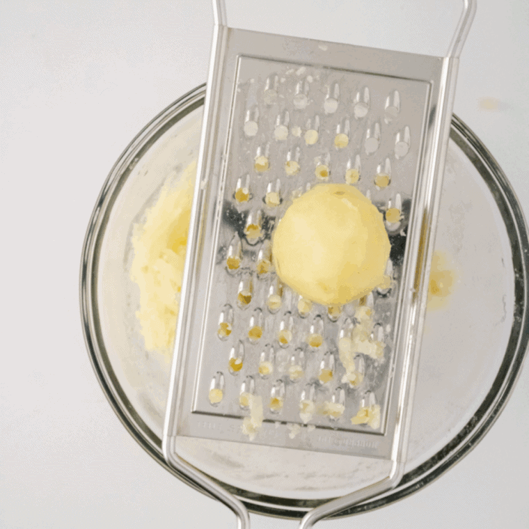 Mixing shredded potatoes with diced onion, salt, and black pepper in a large bowl