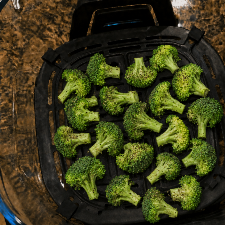 Seasoned broccoli florets arranged in a single layer on the Ninja Crispi crisper plate