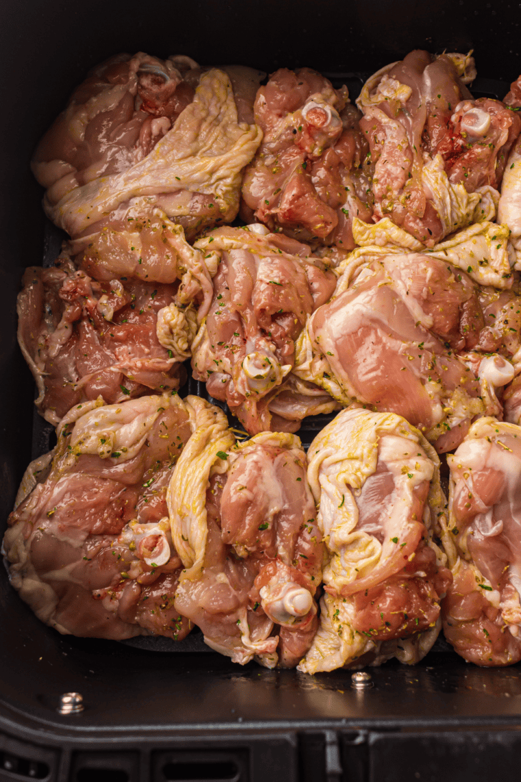 Preheating air fryer to 380°F and placing marinated chicken thighs in a single layer, skin side down.