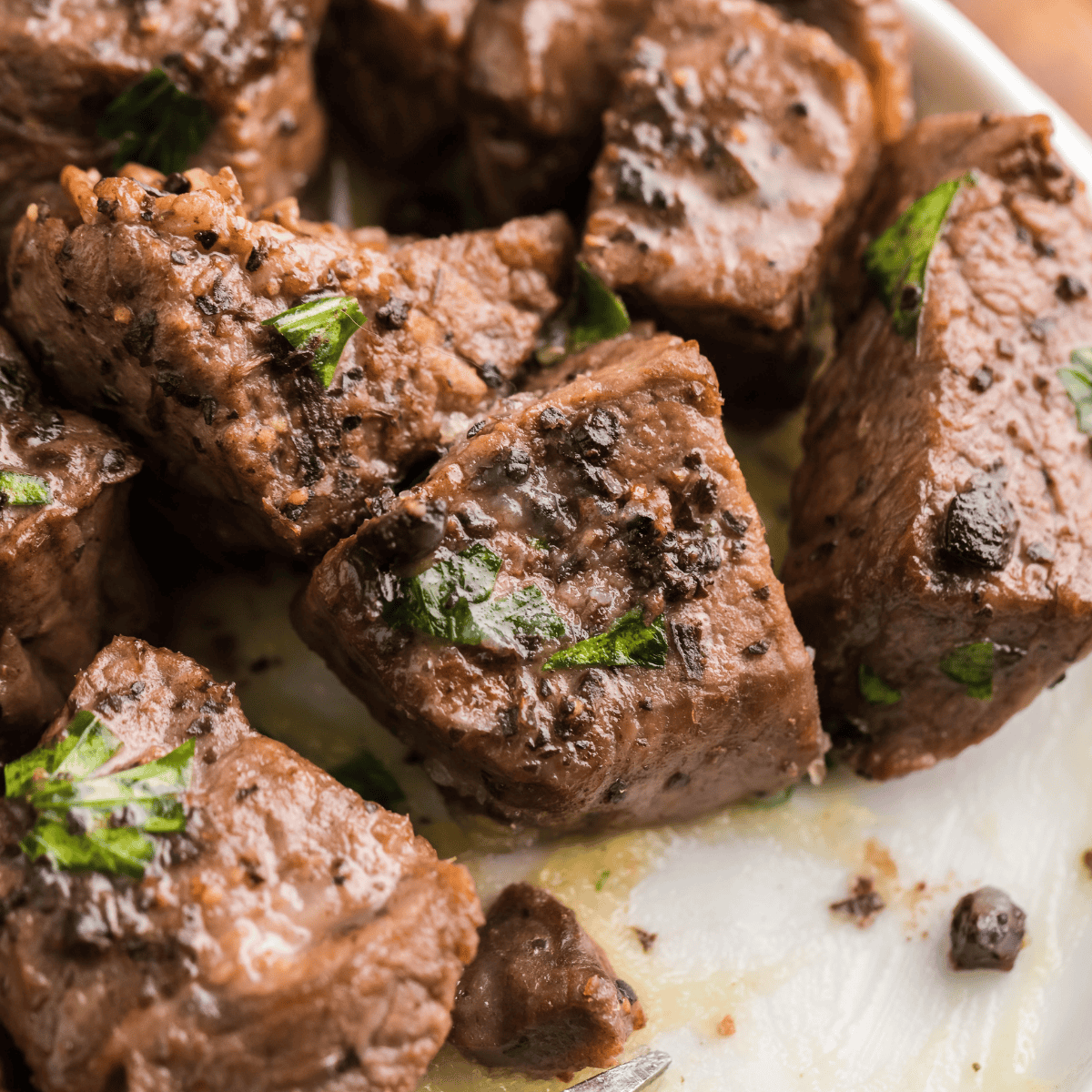 Plate of Texas Roadhouse-style beef tips with mushrooms and brown gravy served over mashed potatoes.