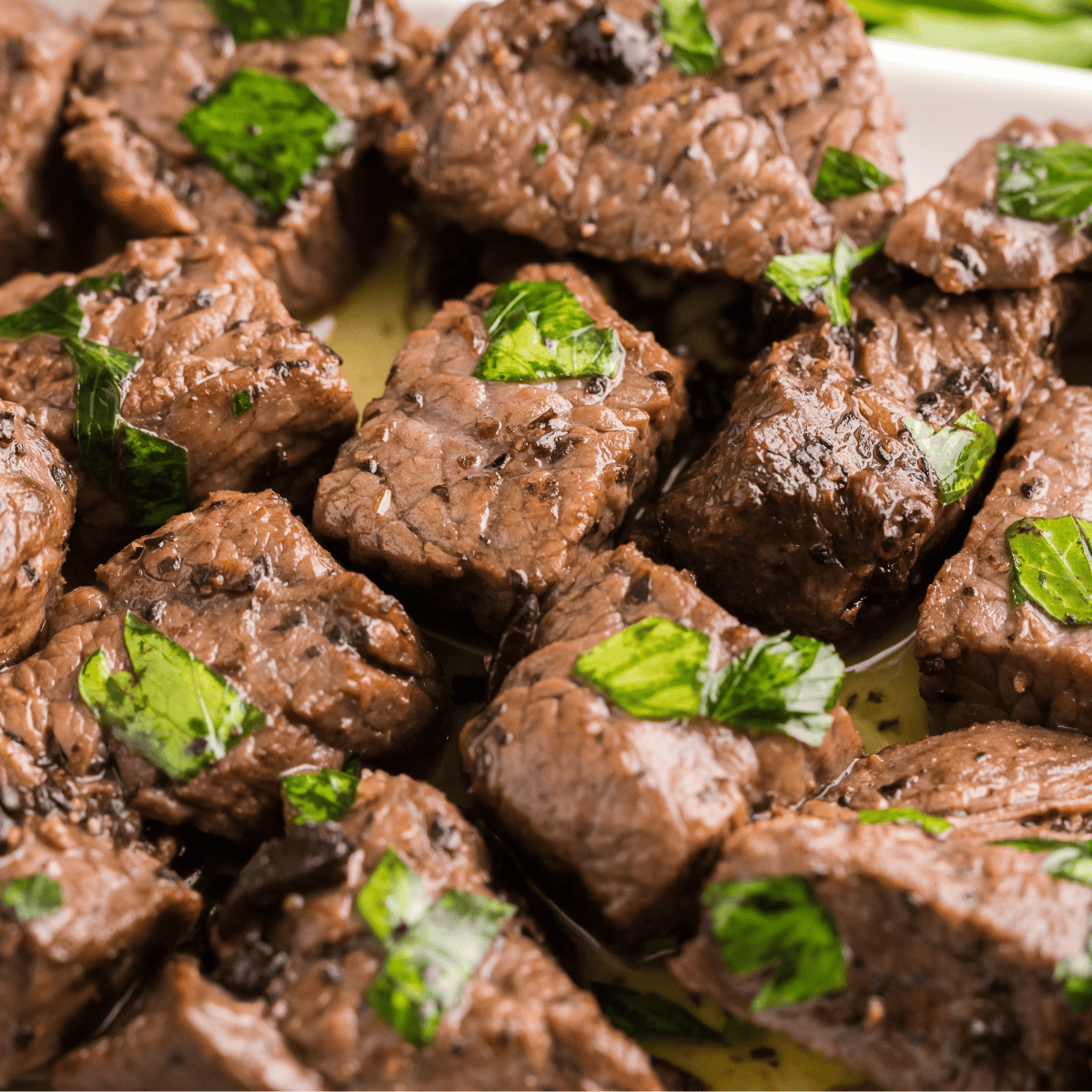 Juicy Texas Roadhouse sirloin beef tips with garlic butter and herbs on a plate.